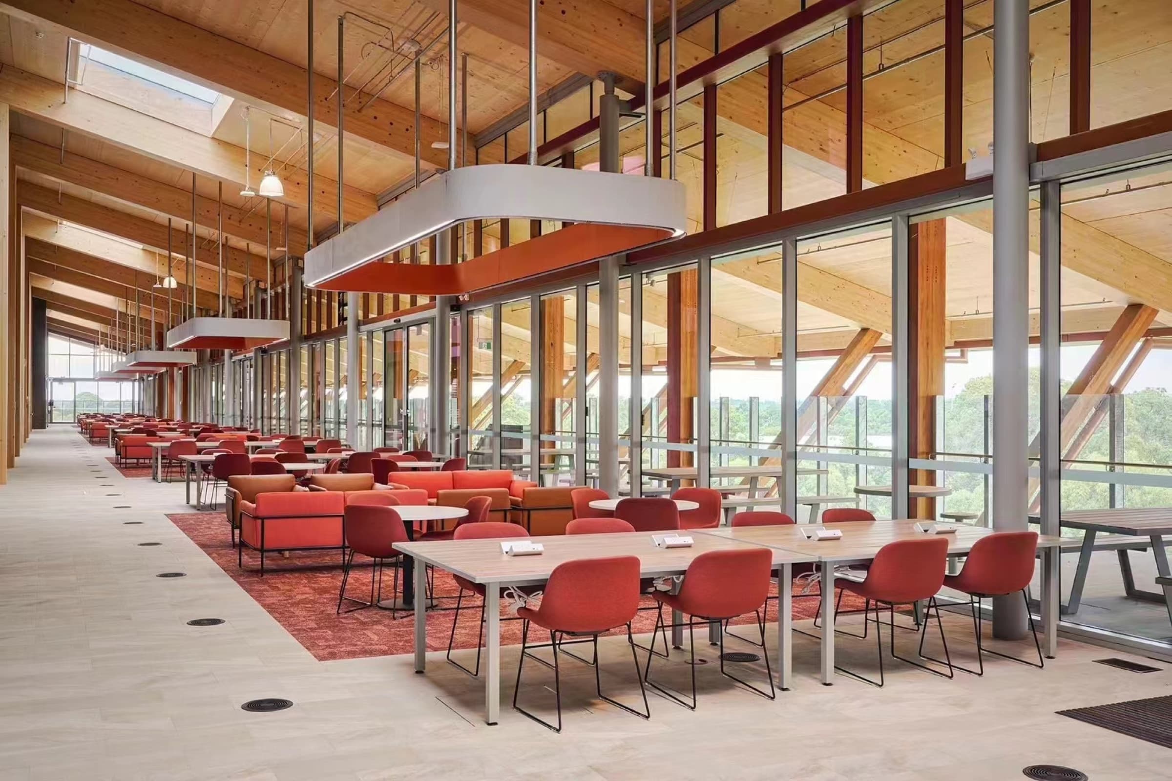Long timber study hall furnished with red chairs at Murdoch University